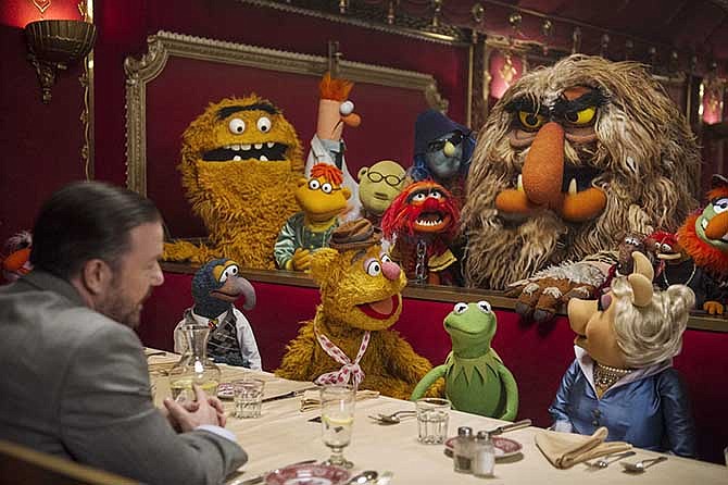 This image released by Disney shows Ricky Gervais, left, with the muppets in a scene from "Muppets Most Wanted." 