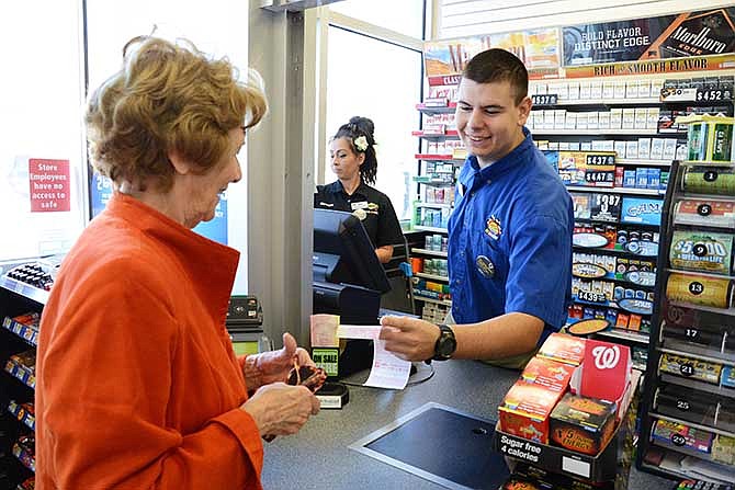 Brady Cardenas, left, picks up Mega Millions tickets from Gino, and Andrea at the Sunoco convenience store in Merritt Island, Fla., Wednesday, March 19, 2014. One of the two winning tickets in the $400 million Mega Millions drawing was sold at the store. (AP Photo/Florida Today, Craig Bailey)