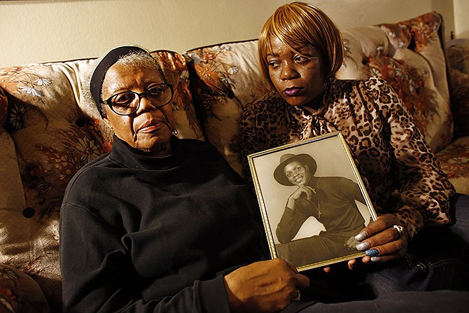 Alma Murdough and her daughter, Cheryl Warner, hold a photo of Murdough's son, at her home in the Queens borough of New York. Jerome Murdough, a mentally ill, homeless former Marine arrested for sleeping in the roof landing of a New York City public housing project, died last month in a Rikers Island jail cell that multiple city officials say was at least 100 degrees when his body was discovered.