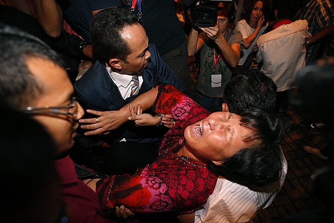 A Chinese relative of a passenger aboard a missing Malaysia Airlines plane is carried out by security officials as she protests before a press conference at a hotel in Sepang, Malaysia on Wednesday.