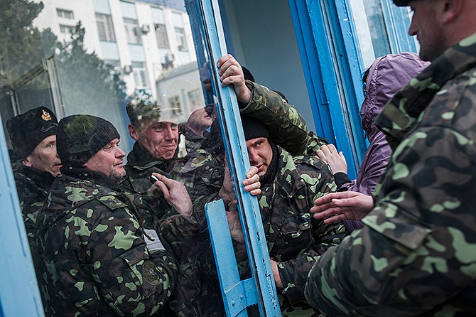 Pro-Russian self-defense force members get through an entrance to the Ukrainian Navy headquarters in Sevastopol, Crimea, Wednesday. An Associated Press photographer said several hundred militiamen took down the gate and made their way onto the base. They then raised the Russian flag in the square by the headquarters.