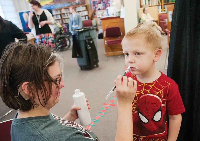 A student at the Missouri School for the Deaf paints a fake milk mustache on a preschooler inside the school's library on Thursday. During a "Reading is Fundamental" event, which encouraged reading for pleasure, students from various grade levels learned about animation and video through hands-on activities. Three preschool boys starred in a milk mustache commercial that will play in the school cafeteria.