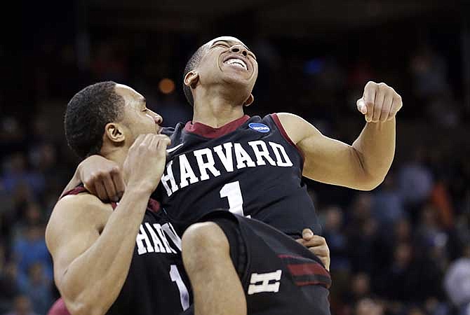 Harvard's Siyani Chambers, right, leaps into the arms of teammate Brandyn Curry after the team beat Cincinnati in the second round of the NCAA college basketball tournament in Spokane, Wash., Thursday, March 20, 2014. Harvard won 61-57.