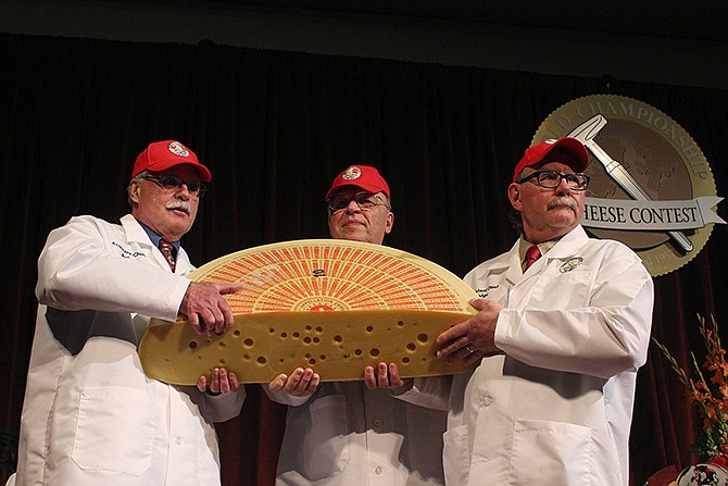 Three judges for the 2014 World Championship Cheese Contest hold the champion, a Swiss Emmentaler on Wednesday in Madison, Wis. Cheesemaker Gerard Sinnesberger from Kaserei Sinnesberger in Gams, Switzerland, took top honors out of 2,615 entries from 22 countries. 