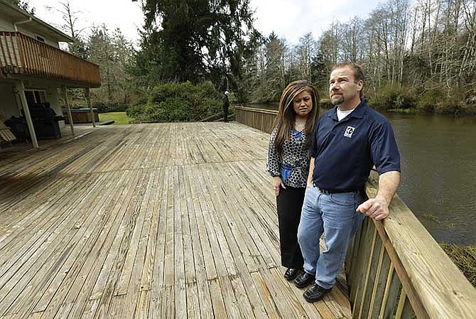 Darrin Moir, right, and his wife Leonor Moir, stand Monday, March 18, 2014 on the deck of their house, which is located along the Little Hoquiam River in Hoquiam, Wash. The Moirs currently pay about $1,700 annually for flood insurance, even though they say they have never had a major flooding incident since buying their home in 1996. Possible rate increases could up their premiums to more than $9,000 a year, which they say could prevent them from eventually selling their home.