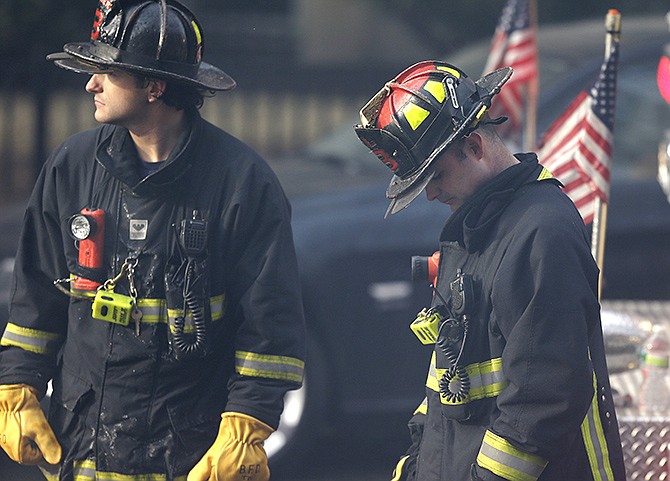 A firefighter lowers his head Wednesday at the scene of a multi-alarm fire at a four-story brownstone in the Back Bay neighborhood near the Charles River in Boston.