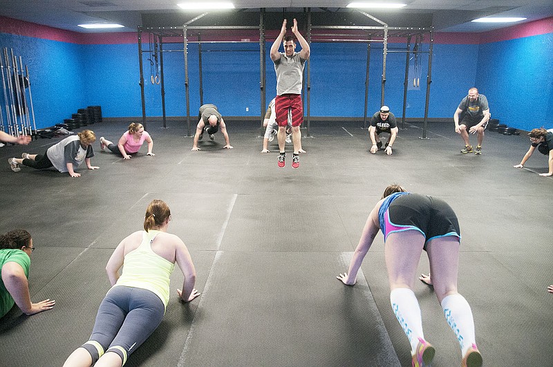 Brad Vickers, trainer and owner at the new Bluff Street Cross Fit, leads a class through an exercise called burpees Wednesday night.