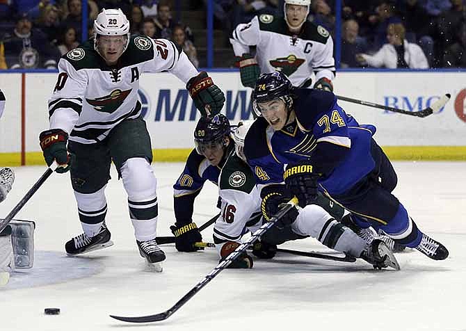 St. Louis Blues' T.J. Oshie (74) and Minnesota Wild's Ryan Suter (20) reach for a loose puck during the second period of an NHL hockey game Thursday, March 27, 2014, in St. Louis.