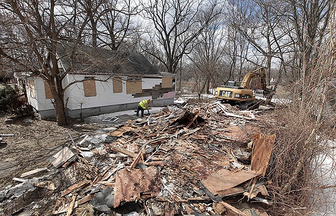 An excavator tears down a house in Detroit's Brightmoor area on Monday. For years, Brightmoor area residents pleaded with the city to demolish vacant homes that scavengers have stripped of wiring and plumbing and anything of value. Some structures are already gone, and now officials aim to do much more, possibly tearing down as many as 450 empty houses each week across more than 20 square miles of this bankrupt city - a vast patchwork of rotting homes comparable to the size of Manhattan.