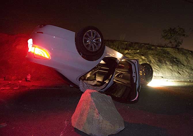 A car sits rolled over in the wake of Friday nights March 28, 2014 earthquake on Carbon Canyon Road in Brea, Calif., near Olinda Village.