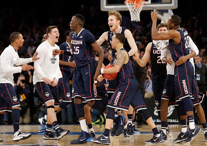 Connecticut players celebrate after beating Michigan State 60-54 in a regional final at the NCAA college basketball tournament, Sunday, March 30, 2014, in New York.