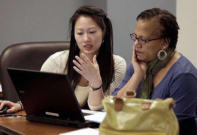 Counselor Jennifer Chen, left, assist Josette Jackson with questions while trying to enroll for health insurance Monday in St. Louis.