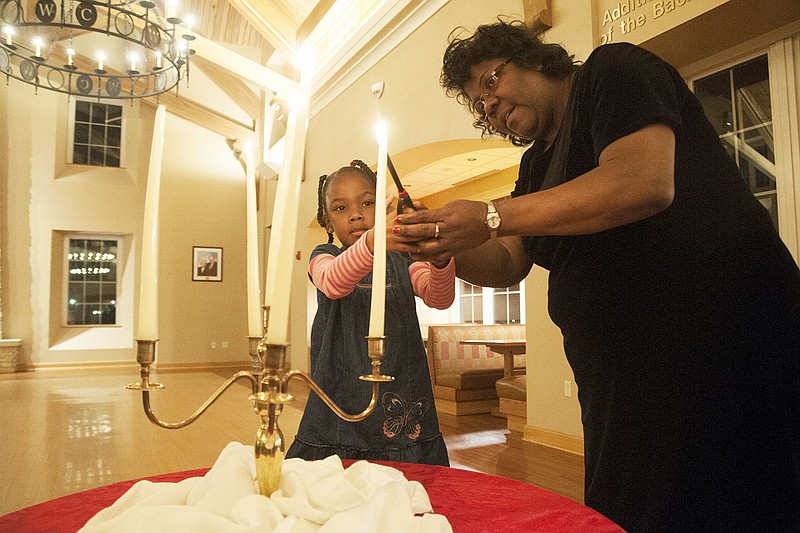 Taji Braxton, 6, of Fulton lights a candle with the help of her grandmother Carmen Brandt Saturday during the first Jane Bierdeman-Fike Humanitarian Award Program and Celia Commemoration at Backer Dining Hall. Brandt sits on the Fulton Human Rights Commission and was an organizer of the event, which brings the community together to commemorate Celia, a southern Callaway County slave who was hanged for murdering her sexually abusive master. This year was the first time the commission gave the Jane Bierdeman-Fike Humanitarian Award. The recipient of the honor was Nancy McCue of Fulton.