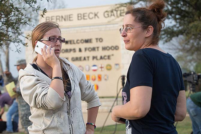 While standing outside of the Bernie Beck Gate at Fort Hood, Krystina Cassidy and Dianna Simpson attempt to make contact with their husbands who are inside the base during a lockdown on Wednesday, April 2, 2014, in Fort Hood, Texas.