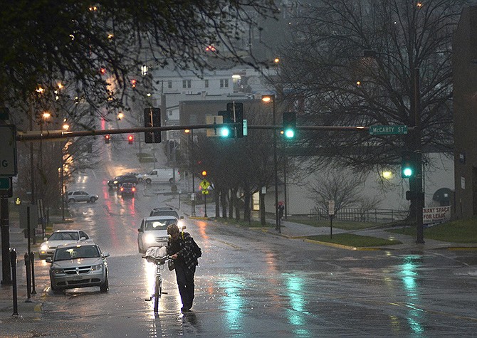 A pedestrian walks his bike through a downpour just as the tornado sirens sounded during a storm passing through Jefferson City Thursday evening, April 3, 2014.