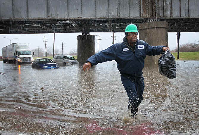 Darryl Hamilton walks away from his minivan stuck in floodwater in St. Louis on Wednesday, April 2, 2014. Three vehicles became stuck in the high water caused by a downpour. Everyone in the vehicles was able to walk out of the water on their own or were helped by police to dry land. 