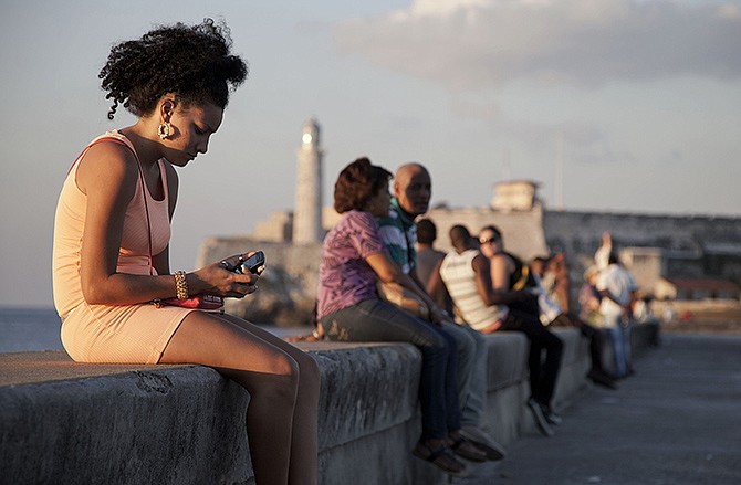 A woman uses her cellphone as she sits on the Malecon in Havana, Cuba. The U.S. Agency for International Development masterminded the creation of a "Cuban Twitter," a communications network designed to undermine the communist government in Cuba, built with secret shell companies and financed through foreign banks, The Associated Press has learned.