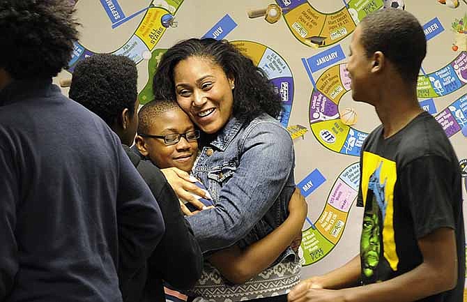 Youth development programmer Jamee DeWalt gives Isaiah Curtis a congratulatory hug after receiving his certificate following a graduation ceremony for boys in the Passport to Manhood program at the Boys and Girls Club of the Capital City teen center on Friday.