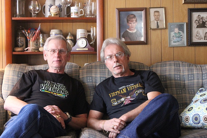 Brothers Bob Olson and Steve Radliff sit in Olson's home, together for the first time in six decades. Despite growing up in different adoptive families, the brothers learned they had plenty in common. Both were Vietnam veterans, though serving at different times and in different branches of the military, and both have a fondness for sports. Other common bonds that unite them sit in the background: German steins from the two's birth country, and portraits of Olson's - and Radliff's - relatives.