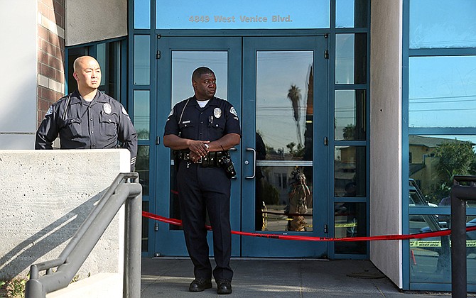 Los Angeles police officers stand outside the West Traffic Division station on Tuesday after an officer was shot and wounded inside the station Monday evening. 