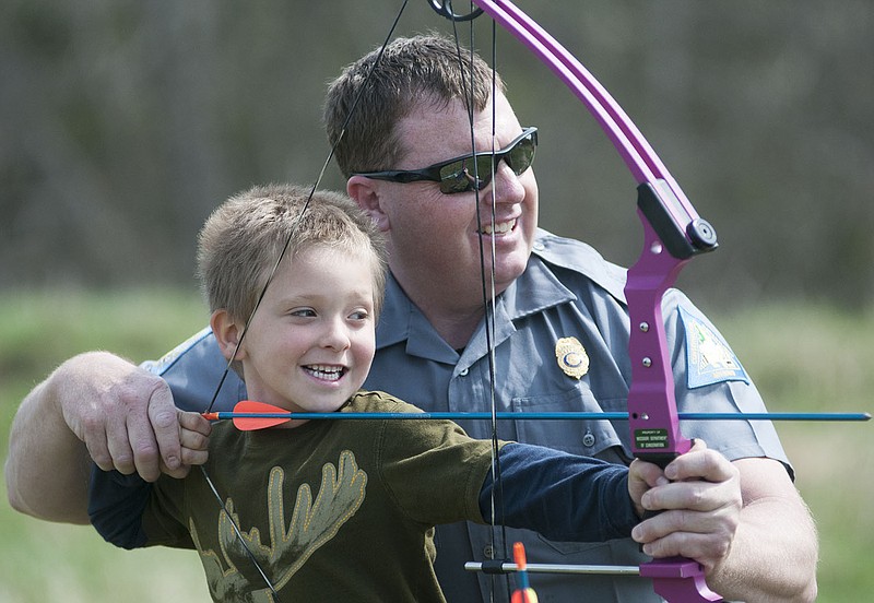 A ranger with the Missouri Department of Conservation helps Alex Lock, 5, of New Bloomfield aim his bow and arrow Saturday during the Midwest Foster Care and Adoption Association's "Family Fun Fishing" event. The non-profit organization supports adoptive and foster parents. The Callaway County United Way donated a $1,000 grant to the organization in order to provide supplies and educational kits for the children to fish, learn how to use bows and arrows and learn about the outdoors.