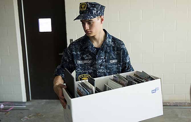 Sea Cadet Cameron Engelbrecht moves a box along a human chain formed by the cadets Saturday afternoon while the U.S. Navy's youth organization helped move items to the new location of the Missouri Military History Museum.