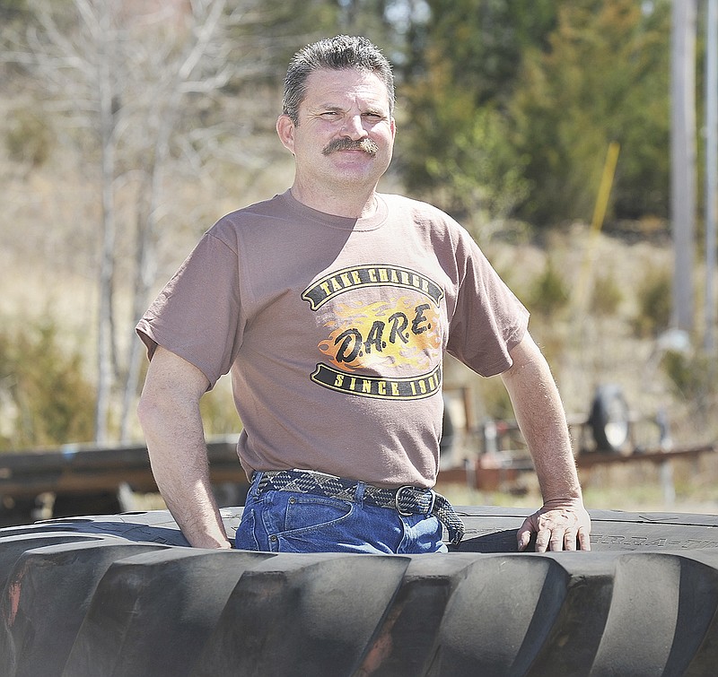 Gene Patterson stands inside one of the monster-sized truck tires at his workplace.