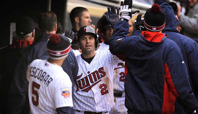Minnesota Twins' Brian Dozier, center, celebrates in the Twins dugout after scoring the go-ahead run on a throwing error by Kansas City Royals pitcher Wade Davis during the ninth inning of a baseball game in Minneapolis, Sunday, April 13, 2014. Minnesota won 4-3.