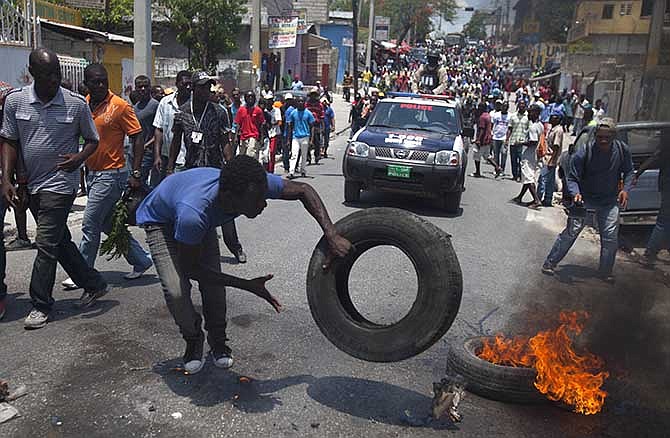 A protester burns tires on the street during a protest against President Michel Martelly's government in Port-au-Prince, Haiti, Tuesday April 15, 2014. Those demonstrating called for the resignation of Martelly.