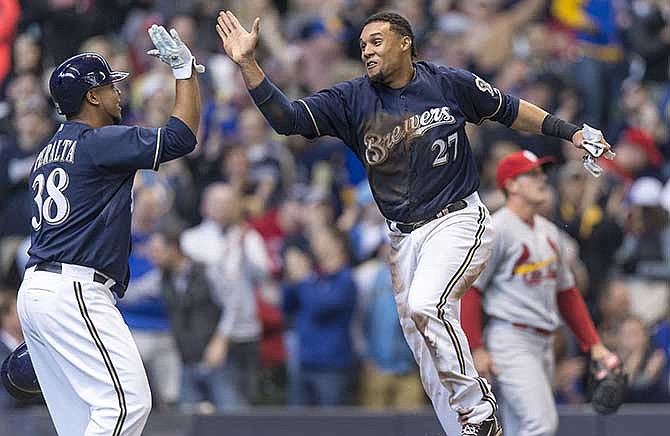 Milwaukee Brewers' Carlos Gomez (27) and Wily Peralta (38) high-five after Gomez scored on Jonathan Lucroy's two RBI single off of St. Louis Cardinals' Seth Maness during the fifth inning of a baseball game Wednesday, April 16, 2014, in Milwaukee.