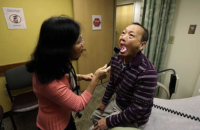 In this Friday, March 1, 2013 file photo, Chan Lai Ly, right, has his mouth examined by Honghue Duong, a physician's assistant, as part of a regular check-up related to his diabetes at International Community Health Services in Seattle. 