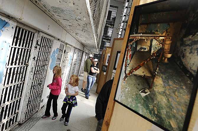 Young viewers peek inside Housing Unit 3's empty cells in September 2012 while others look over the photos in the prison-themed art and photography competition during the Missouri State Penitentiary "Inside the Walls" 176th anniversary event.