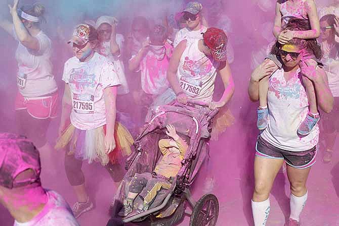 Participants of all ages in the Central Missouri Color Vibe Race run through plumes of pink and blue color powder at the start of the 5K at the corner of High and Madison streets on Saturday morning. Proceeds from the race benefited We Can!, which provides resources and promotes healthy lifestyles for families and children.