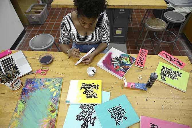 MU freshman Karen Spears works in the MU craft studio in Columbia, Mo., on Thursday, April 10, 2014. Spears, a lettering artist, makes free-handed paintings and sells them in the MU Quirks store and on Etsy. (AP Photo/Missourian, Marissa Weiher)