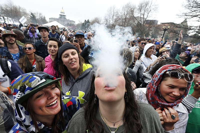 With the Colorado state capitol building visible in the background, partygoers dance and smoke pot on the first of two days at the annual 4/20 marijuana festival in Denver on Saturday. The annual event is the first 420 marijuana celebration since retail marijuana stores began selling in January.