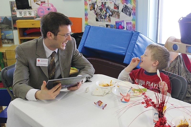 Clayton Kennedy of the American Red Cross shares a laugh with 4-year-old Kenny over a storybook and chili during last yea'rs 100-Man Luncheon. This year's event on April 24 invites positive male role models from throughout the community to spend time with Fulton's preschoolers.