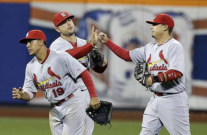 St. Louis Cardinals' Jon Jay, left, Matt Holliday, and Allen Craig, right, celebrate after a baseball game against the New York Mets Tuesday, April 22, 2014, in New York. The Cardinals won the game 3-0. 