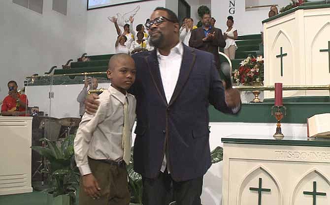 In an April 10, 2014, image provided by WXIA-TV, 9-year-old Willie Myrick is embraced by Grammy Award-winning gospel singer Hezekiah Walker in front of the congregation at Mt. Carmel Baptist Church in Atlanta. Police say Myrick was abducted from his driveway but was released after singing the gospel song "Every Praise" until the abductor released him. 