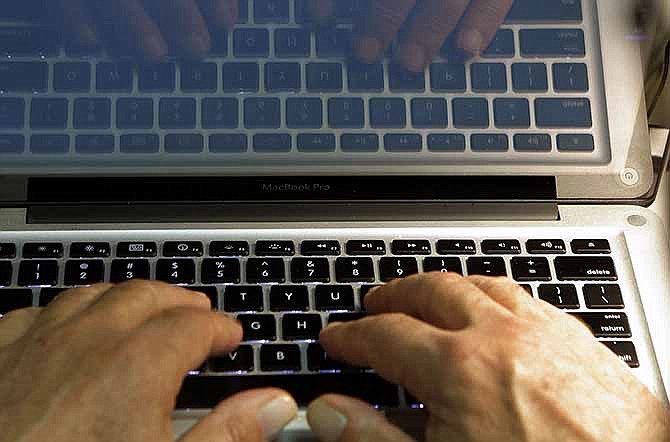 In this Wednesday, Feb. 27, 2013 photo illustration, hands type on a computer keyboard in Los Angeles. In the wake of the Heartbleed security threat, many security experts recommend a second layer of authentication _ typically in the form of a numeric code sent as a text message. You enter that code on the website to verify that it's really you and not a hacker who doesn't have your phone. 