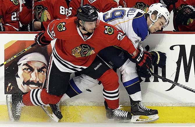 St. Louis Blues' Adam Cracknell, right, is checked by Chicago Blackhawks' Brandon Saad during the first period in Game 4 of a first-round NHL hockey playoff series in Chicago, Wednesday, April 23, 2014.