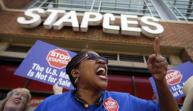 U.S. Post Office employee Detra Parker chants during a protest outside a Staples store, Thursday, April 24, 2014, in Atlanta. Thousands of postal workers picketed outside Staples stores nationwide Thursday to protest a pilot program that allows the office supply chain to handle U.S. mail. The American Postal Workers Union fears layoffs and post office closings and says that unlike retail workers, postal workers "have taken an oath to protect the sanctity of the mail." 