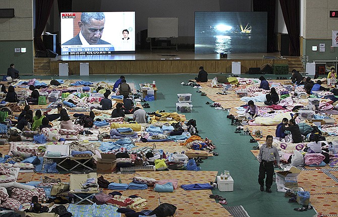 A TV screen shows U.S. President Barack Obama paying a silent tribute for the victims of South Korea's sunken ferry as relatives of victims look on at a gymnasium in Jindo, South Korea.