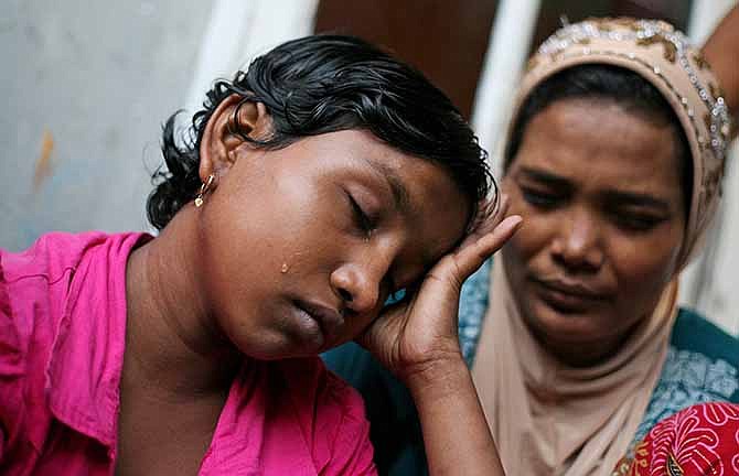  In this Oct. 19, 2013 photo, young ethnic Rohingya asylum seeker Senwara Begum, left, cries at a temporary shelter in Medan, North Sumatra, Indonesia after making a phone call to her family in Myanmar. After her tiny Muslim village in Myanmar's northwest Rakhine had been destroyed in a fire set by an angry Buddhist mob, she and her brother became separated from their family.