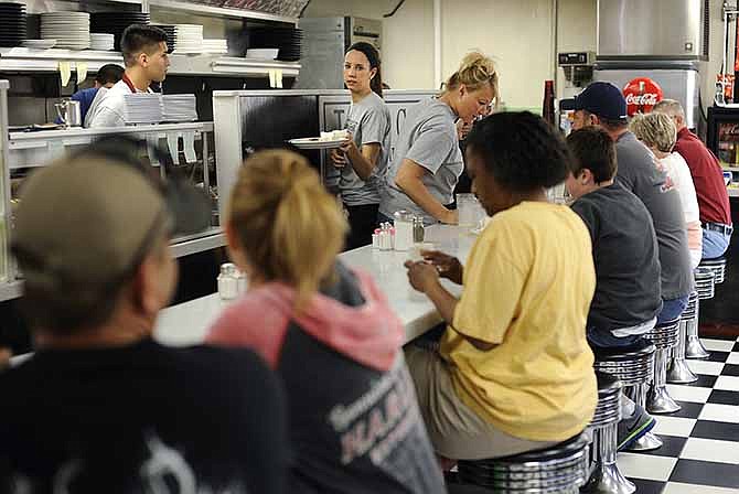 Waitresses Darian Werdehausen, center, and Stacey Kloeppel, right, tend to diners seated at the counter during the morning breakfast rush at the newly reopened Towne Grill on Saturday in downtown Jefferson City.