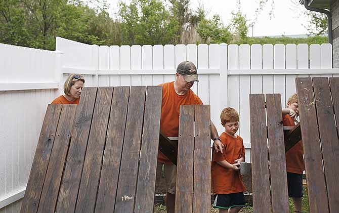 Carmen Blaise (left) and her husband, Brock Blaise, varnish two picnic tables at Pathways Community Help with their sons Gabe, 7, and Beau, 8, as part of the third annual Serve Jeff City clean-up Saturday morning.