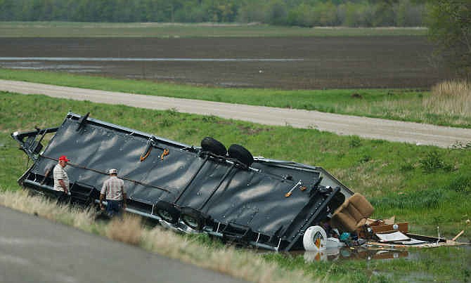Motorists check out a travel trailer damaged in an accident involving high winds from a severe thunderstorm that passed near Rich Hill, Mo., Sunday, April 27, 2014.