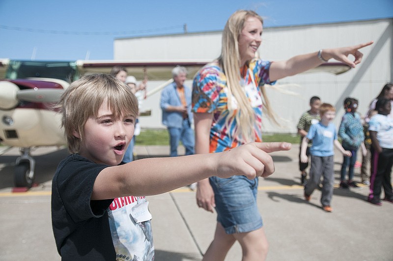 A second grader from Rock Bridge Elementary School in Columbia points along with teacher Kaitlin Nichols as an airplane takes off at the Elton Hensley Airport in Fulton. A grant from the Kingdom Pilots Association provided transportation for a field trip to the airport where pilots taught the children aviation basics and allowed them to sit inside several airplanes.