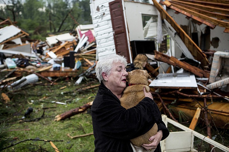 Constance Lambert embraces her dog after finding it alive Monday when returning to her destroyed home in Tupelo, Miss. Lambert was at an event away from her home when the tornado struck and rushed back to check on her pets.