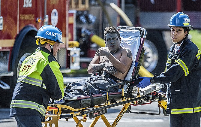 An injured worker is moved toward a waiting ambulance after an explosion was reported at a business in La Habra, Calif., on Tuesday. Authorities say eight people have been hurt, three critically, in the explosion and fire.