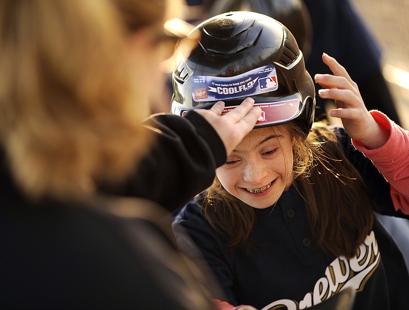 Suzanne Schnieders, right, is all smiles as Alisha Rehagen, left, helps her put on her batting helmet before stepping out of the dugout for an at bat during Miracle League baseball games at Binder Park on Friday.